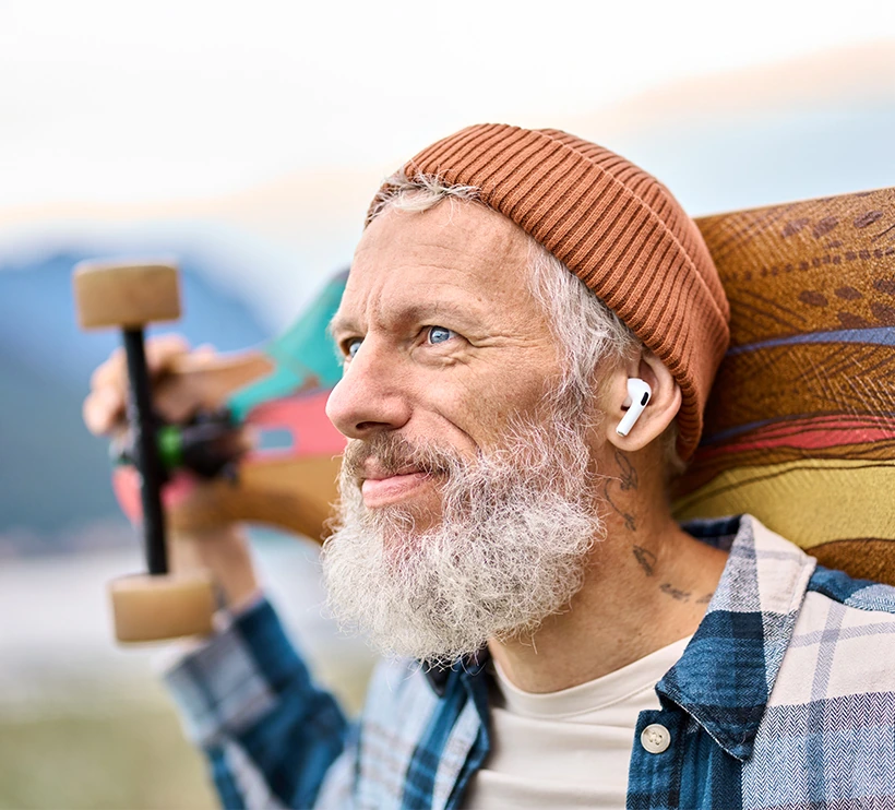 mature bearded man holding a longboard